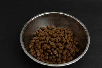 Dry dog food in an aluminum plate on a black background, dog food