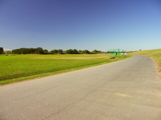 秋の平日の江戸川河川敷の舗装路と野球場風景