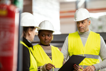 A multiracial group of people is working in a distribution warehouse, the manager is giving instructions to the workers.