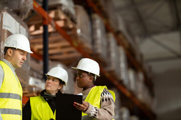 A multiracial group of people is working in a distribution warehouse, the manager is giving instructions to the workers.