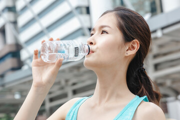 Asian lady drinking water sport healthy lifestyle outdoors in building city background