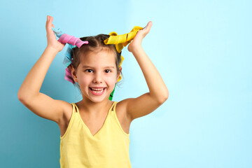 Little girl with curlers on blue background with copy space