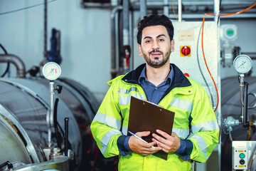 Hispanic smart confident engineer male service worker in factory portrait in boiler water pipe room.