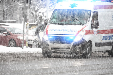 911 ambulance van rushing through traffic during heavy winter snowfall conditions. © astrosystem