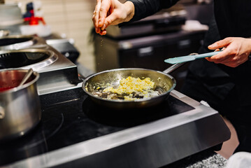 man chef cooking tasty scrambled eggs in frying pan on kitchen