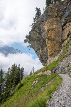 hiking trail around lake Oeschinensee, under overhanging rocks