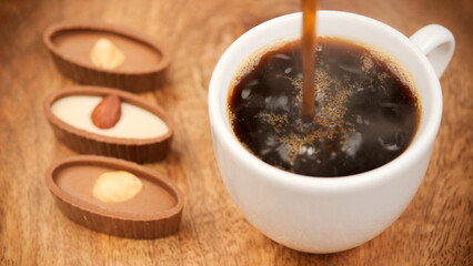 Coffee with chocolate candy. Pouring black coffee in white cup