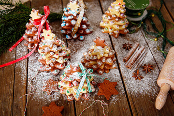 Home made baked Christmas gingerbread tree as a gift for family and friends on wooden background. With colorful lights from Christmas tree on background. With icing sugar gift for xmas