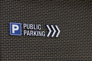 Parking road sign with arrows on a brick wall. 