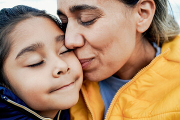 Mother and daughter having tender moment outdoor in winter day - Latin family and love concept