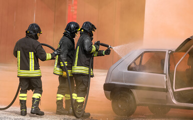 firefighters extinguish the fire of the crashed car after the accident