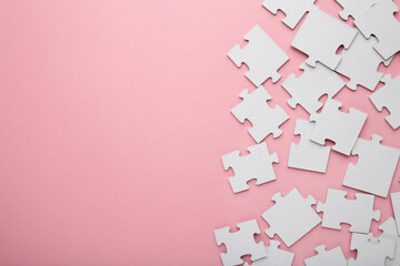 Uncompleted elements of a white puzzle on pink background. Space for text