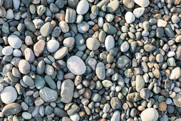 Texture of sea polished stones on a beach closeup top view different shapes
