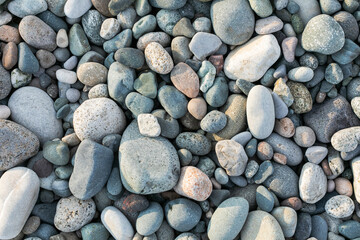 Texture of sea polished stones on a beach closeup top view different shapes
