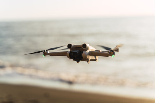 small drone flying in the middle of a sandy beach at sunset
