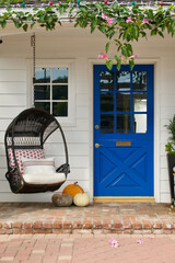 beach bungalow with brick porch, egg chair and vibrant blue front door - obrazy, fototapety, plakaty