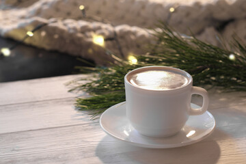 Christmas latte coffee on a white wooden table with pine tree and bokeh lights decor. cozy winter holiday morning. front view.
