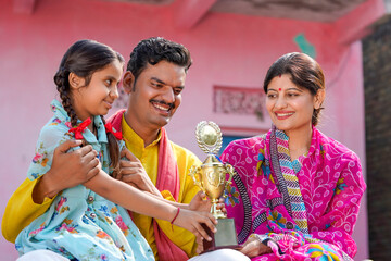 Indian little girl child holding winning trophy with parents