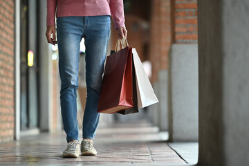 Unrecognizable woman holding shopping paper bags in hands walking outdoor at the shopping district of a city
