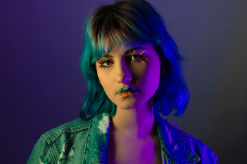 Portrait of young stylish woman posing indenim jacket, blue and yellow tones of clothes in Ukrainian colors style, flowers art on lips