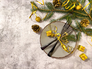 Christmas table set with a black fork and knife tied with a gold ribbon and with a festive decoration on a light background.New year New year postcard with copy space.