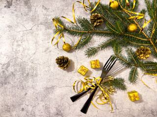 Christmas table set with a black fork and knife tied with a gold ribbon and with a festive decoration on a light background.New year New year postcard with copy space.