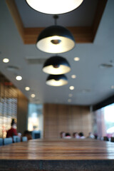 Closeup the edge of wooden table in the cafe with blurred background of modern interior design room and lighting lamp