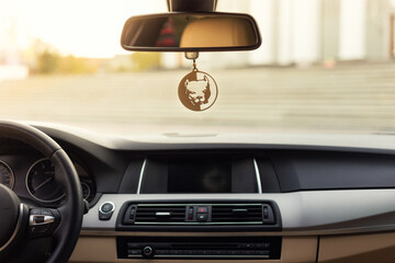View from the car in the foreground dashboard with a steering wheel and a rear-view mirror. The sun...