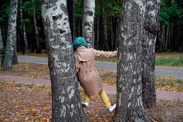 A girl child stands at the cross between the trees. Walk and in the forest park, pastime and outdoor recreation