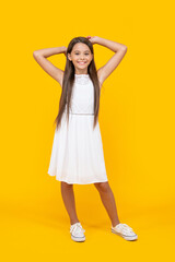 cheerful teen child in white dress standing on yellow background