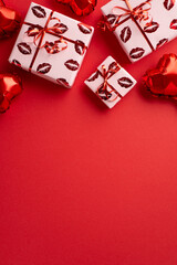 Valentine's Day concept. Top view vertical photo of heart shaped balloons and gift boxes on isolated red background with copyspace