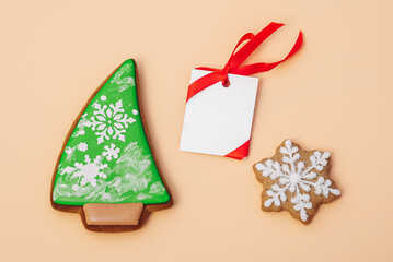 gingerbread cookie of Christmas tree and snowflake and white paper for congratulations text on color background, top view. Close-up. Happy new year and merry christmas concept
