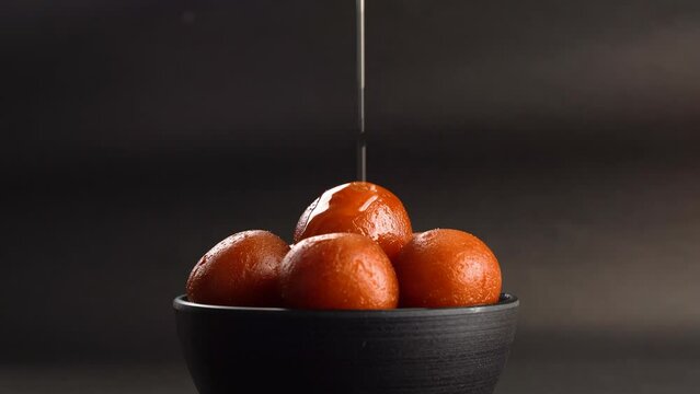 Sweet Gulab Jamun served in bowl, Famous Indian dessert sweets isolated over black indoor studio background
