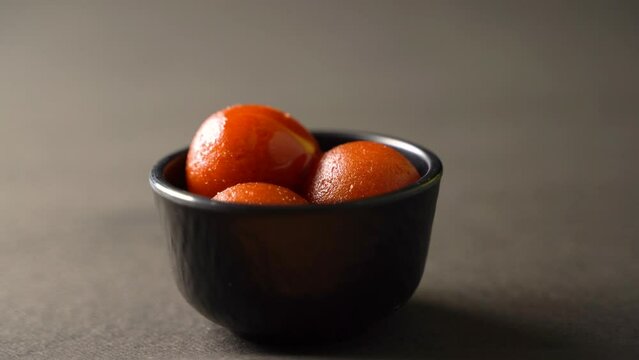 Sweet Gulab Jamun served in bowl, Famous Indian dessert sweets isolated over black indoor studio background