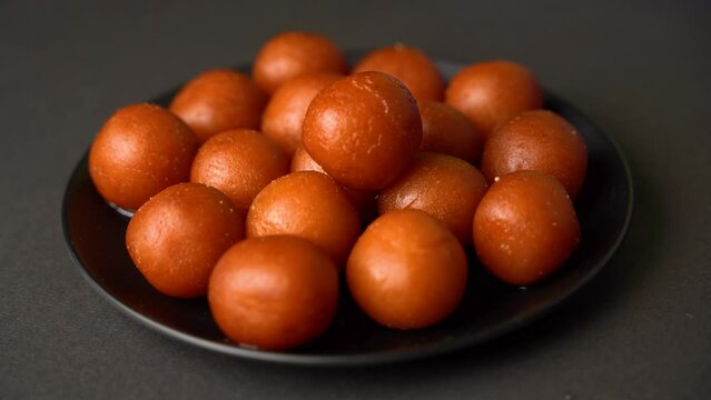 Sweet Gulab Jamun served in a plate, Famous Indian dessert sweets isolated over black indoor studio background