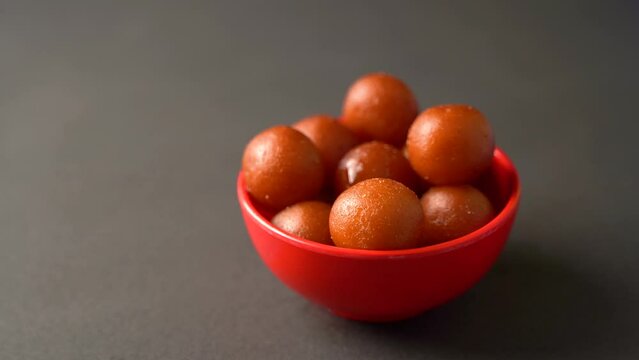 Sweet Gulab Jamun served in bowl, Famous Indian dessert sweets isolated over black indoor studio background