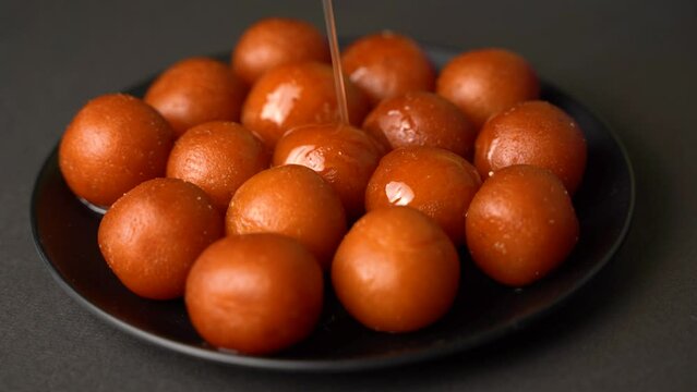 Sweet Gulab Jamun served in a plate, Famous Indian dessert sweets isolated over black indoor studio background