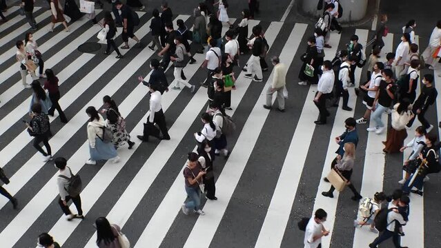 OSAKA, JAPAN : Aerial high angle view of crowd of people walking at zebra crossing near Osaka station in daytime. Commuters at busy rush hour. Japanese lifestyle and business concept. Time lapse shot.