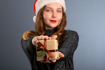 Young caucasian woman holding a present on gray background. isolated