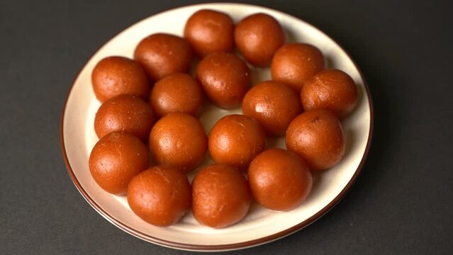 Sweet Gulab Jamun served in a plate, Famous Indian dessert sweets isolated over black indoor studio background