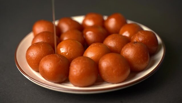 Sweet Gulab Jamun served in a plate, Famous Indian dessert sweets isolated over black indoor studio background