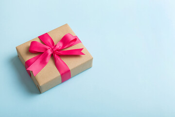 Wrapped christmas or other holiday handmade present in craft paper with colored ribbon. Present box, decoration of gift on table, top view with copy space