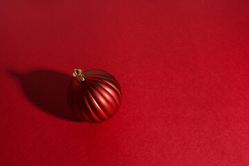 Christmas decoration sphere with shadow on red background, copy space