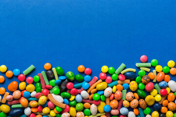 Mixed collection of colorful candy, on colored background. Flat lay, top view. frame of colorful chocolate coated candy
