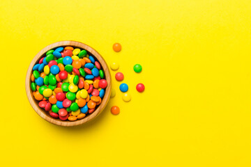Obraz premium Multicolored candies in a bowl on a colored background. birthday and holiday concept. Top view with copy space
