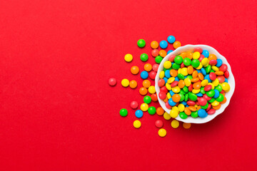 Fototapeta na wymiar Multicolored candies in a bowl on a colored background. birthday and holiday concept. Top view with copy space