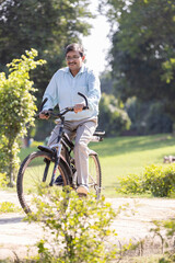 Obraz premium Senior man enjoying and having fun riding bicycle at park