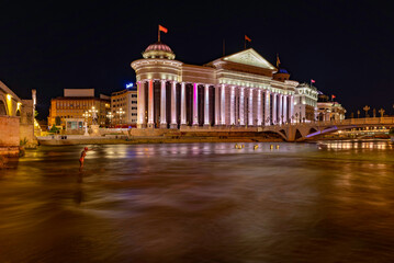 Fototapeta na wymiar Rzeka Wardar i posąg w wodzie pomiędzy mostami wieczorem w Skopje
