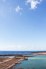 constructions of old salt pans. constructions of the salt pans. Calm ocean. Clear sky with big white fluffy clouds. Sand and rocks. Salt mines of Janubio Lanzarote, Canary Islands, Spain.