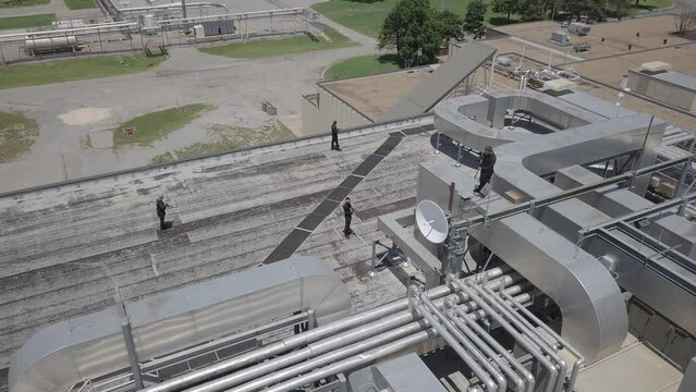 Static aerial shot of armed guards positioned on a rooftop